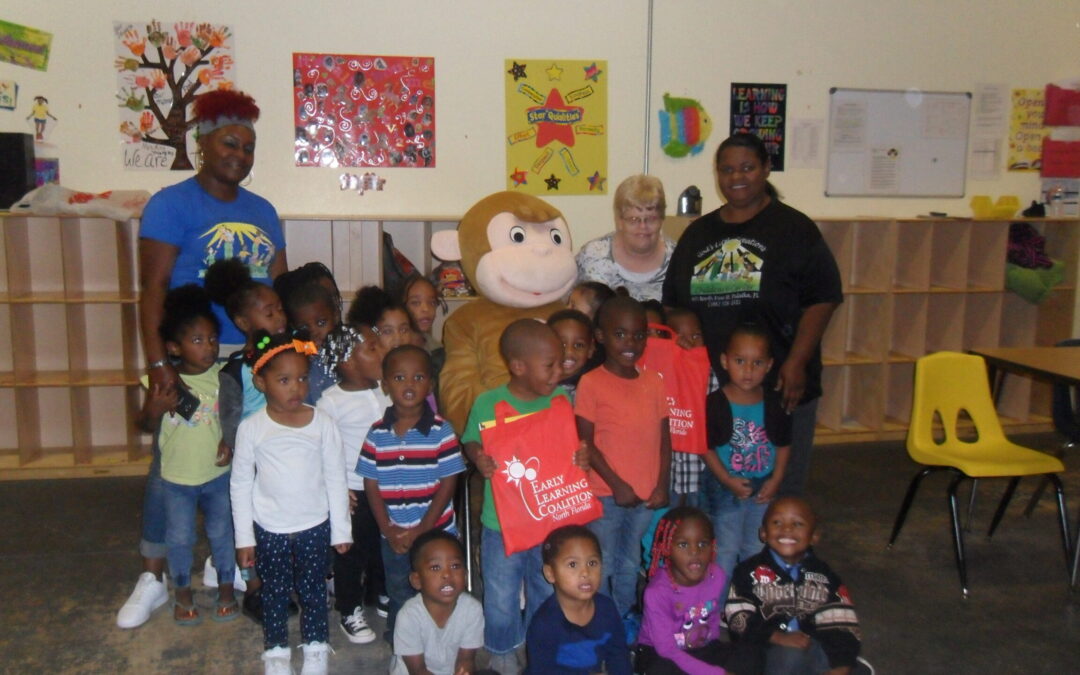 Curious George and ELC of North Florida volunteers deliver book bags to children at God’s Little Creations Learning Center in Palatka.